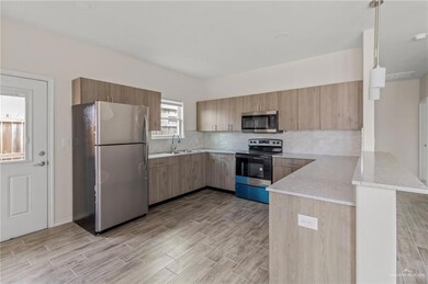 Kitchen with tasteful backsplash, kitchen peninsula, stainless steel appliances, light stone counters, and decorative light fixtures
