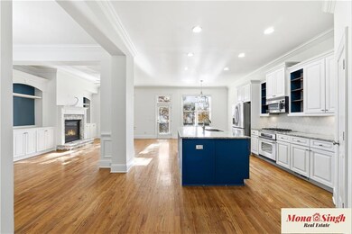 Kitchen with white cabinets, light stone countertops, crown molding, decorative light fixtures, and open floor plan
