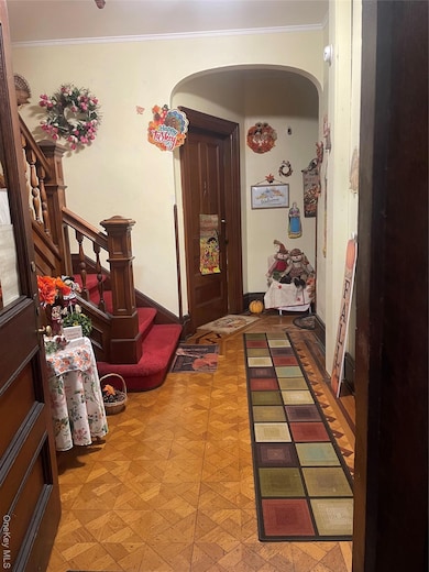 Entryway with arched walkways, ornamental molding, and stairs