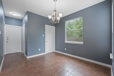 Unfurnished room featuring a chandelier, dark tile patterned floors, and baseboards