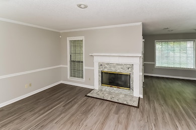 Unfurnished living room featuring a textured ceiling, dark wood finished floors, a fireplace, and ornamental molding