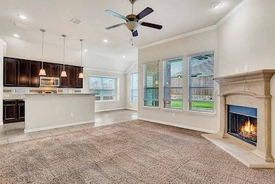 Living room featuring crown molding, light carpet, a ceiling fan, light tile patterned flooring, and vaulted ceiling