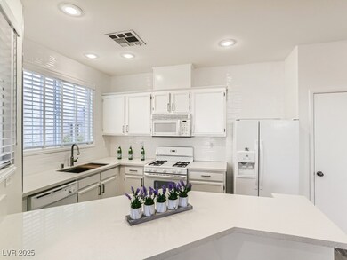Kitchen with light countertops, white appliances,