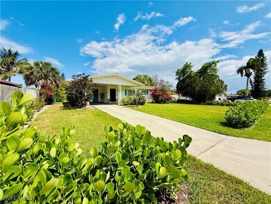 View of front facade featuring concrete driveway, fence, a front yard, and a carport