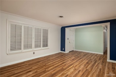 Unfurnished bedroom featuring dark hardwood / wood-style flooring, ornamental molding, and a closet