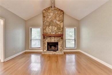 Unfurnished living room with plenty of natural light, wood finished floors, and a stone fireplace