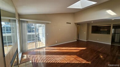 Unfurnished living room featuring vaulted ceiling, dark wood-style floors, and a skylight