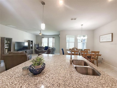 Open floor plan w ceramic tile flooring, extra tall ceilings, 5 1/4” baseboards,Living room w Dinette in background taken from the Kitchen w sliders onto the  covered screened in lanai