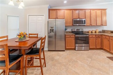 Kitchen featuring stone counters, stainless steel appliances, vaulted ceiling, crown molding, and a notable chandelier