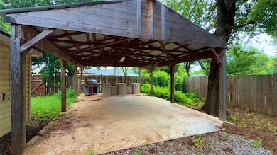 Fenced backyard featuring a carport, a grill, and a patio area