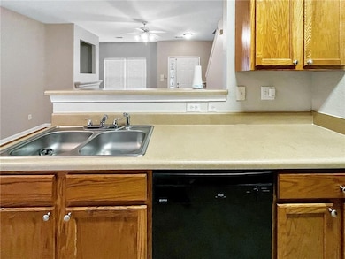 Kitchen featuring dishwasher, a sink, brown cabinets, light countertops, and ceiling fan