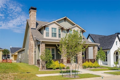 View of front of property with covered porch, a shingled roof, brick siding, and a front lawn