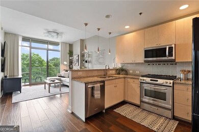 Kitchen featuring stainless steel appliances, light brown cabinets, a peninsula, backsplash, and dark wood-style floors