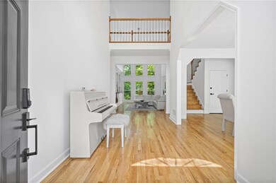 Foyer with stairs, light wood finished floors, baseboards, and a high ceiling