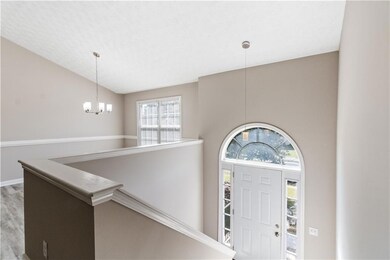 Entrance foyer featuring lofted ceiling, a chandelier, wood finished floors, and a textured ceiling