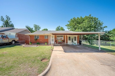 Single story home featuring brick siding, an attached carport, and driveway
