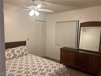 Bedroom featuring ceiling fan, a closet, a textured ceiling, and dark colored carpet