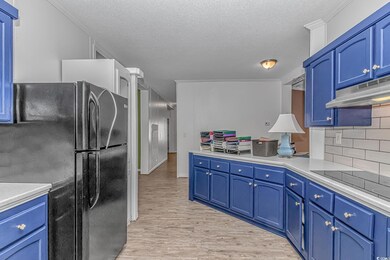 Kitchen featuring black appliances, under cabinet range hood, a textured ceiling, tasteful backsplash, and light wood-style floors