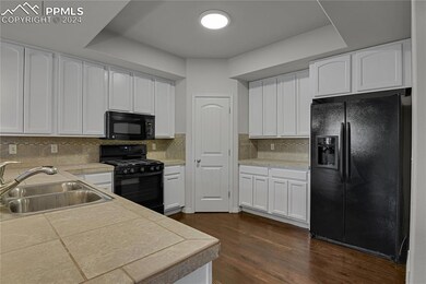 Kitchen with backsplash, black appliances, dark ha
