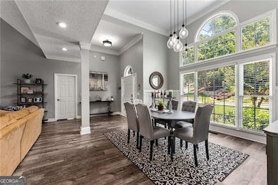 Dining area featuring healthy amount of natural light, a high ceiling, dark wood-style flooring, crown molding, and recessed lighting