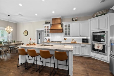 Kitchen featuring stainless steel appliances, a chandelier, tasteful backsplash, a breakfast bar area, and crown molding