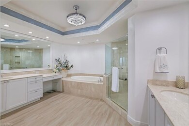 Bathroom featuring a tray ceiling, two vanities, a