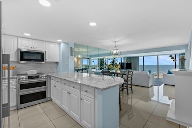 Kitchen with appliances with stainless steel finishes, a peninsula, white cabinets, light tile patterned floors, and open floor plan