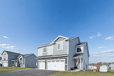 Attractive two-story home with modern gray siding, stone accents, and a spacious three-car garage