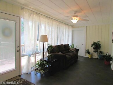 Sunroom. Wall of windows and glass door let in natural light.  Door leads to deck.