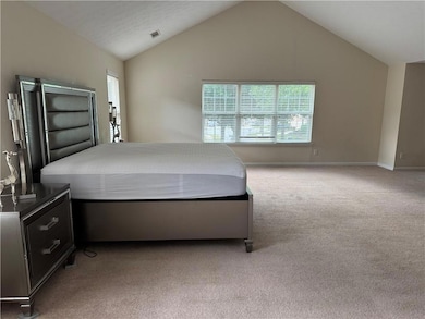 Bedroom featuring light colored carpet, vaulted ceiling, and multiple windows