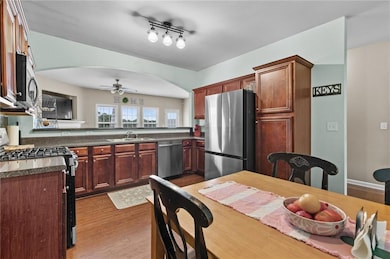 Kitchen with appliances with stainless steel finishes, dark wood finished floors, a ceiling fan, and arched walkways