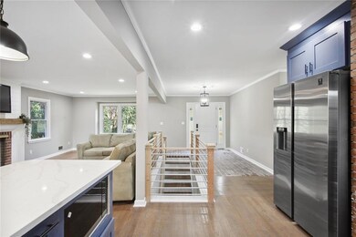 Kitchen with light wood-type flooring, stainless steel refrigerator with ice dispenser, a fireplace, and light stone counters