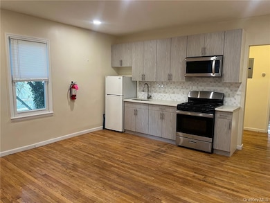 Kitchen featuring gray cabinetry, appliances with stainless steel finishes, sink, decorative backsplash, and light hardwood / wood-style flooring