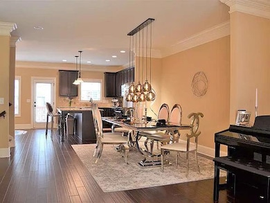 Dining area with baseboards, ornamental molding, and dark wood-style floors