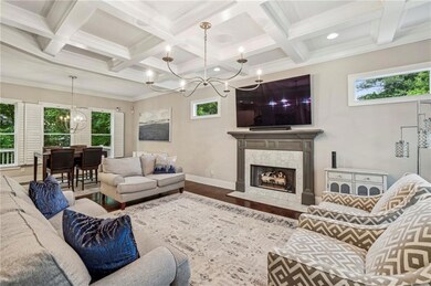 Living room with a chandelier, coffered ceiling, plenty of natural light, wood finished floors, and beamed ceiling