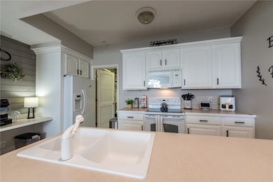 The kitchen features freshly painted cabinets, a dishwasher, electric stove, microwave, refrigerator, garbage disposal, and a desk area.