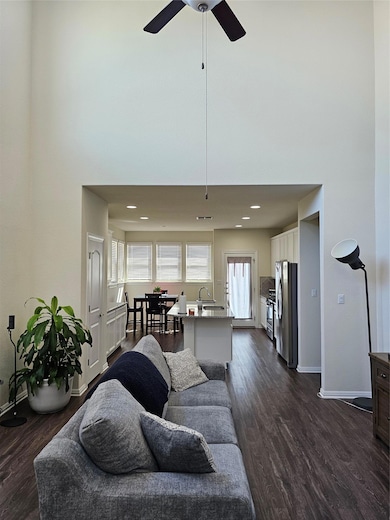 Living room with dark wood-type flooring, a high ceiling, and recessed lighting