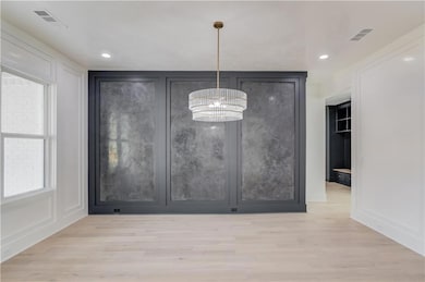 Unfurnished dining area with light wood-style floors, a chandelier, a decorative wall, and recessed lighting