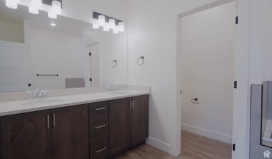 Full bath with double vanity and light wood finished floors