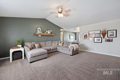 Living room with a ceiling fan, carpet, vaulted ceiling, and a chandelier
