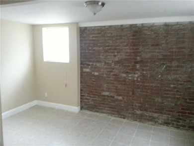 Spare room with brick wall and baseboards