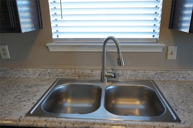 Kitchen view of light stone countertops and a textured wall