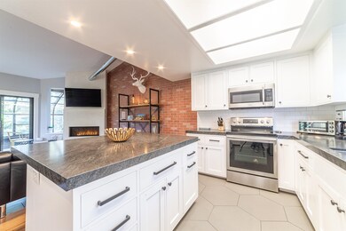 Kitchen featuring appliances with stainless steel finishes, dark countertops, open floor plan, and a large fireplace