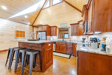 Kitchen with a sink, a breakfast bar area, wood walls, stainless steel appliances, and visible vents