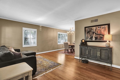 Living room with a chandelier, crown molding, wood finished floors, and baseboards
