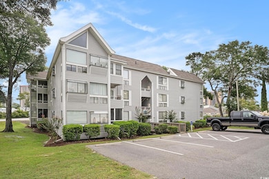 View of apartment building / complex with uncovered parking