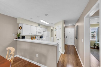Kitchen with white appliances, light countertops, dark wood finished floors, and white cabinets