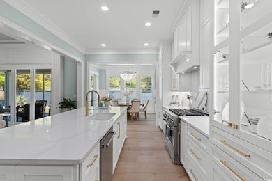 Kitchen with an island with sink, crown molding, white cabinets, stainless steel appliances, and a sink