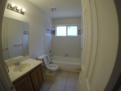 Full bathroom featuring tile patterned floors, vanity, tiled shower / bath combo, and toilet