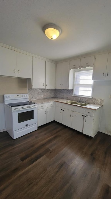 Kitchen featuring stove, dark wood-style floors, white cabinets, and tasteful backsplash
